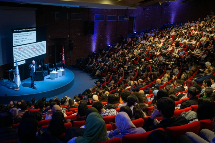 Speaker presenting to large audience in auditorium
